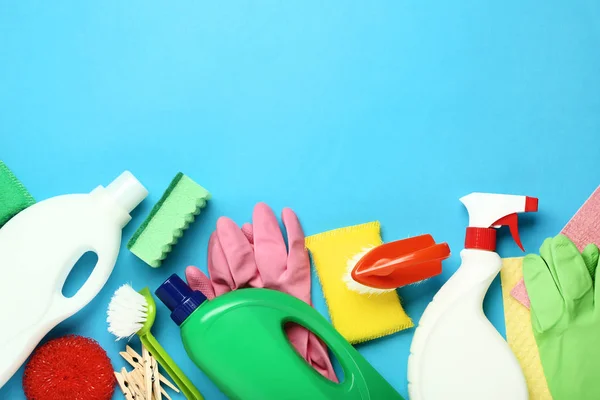 Bottles with detergent and cleaning tools on blue background