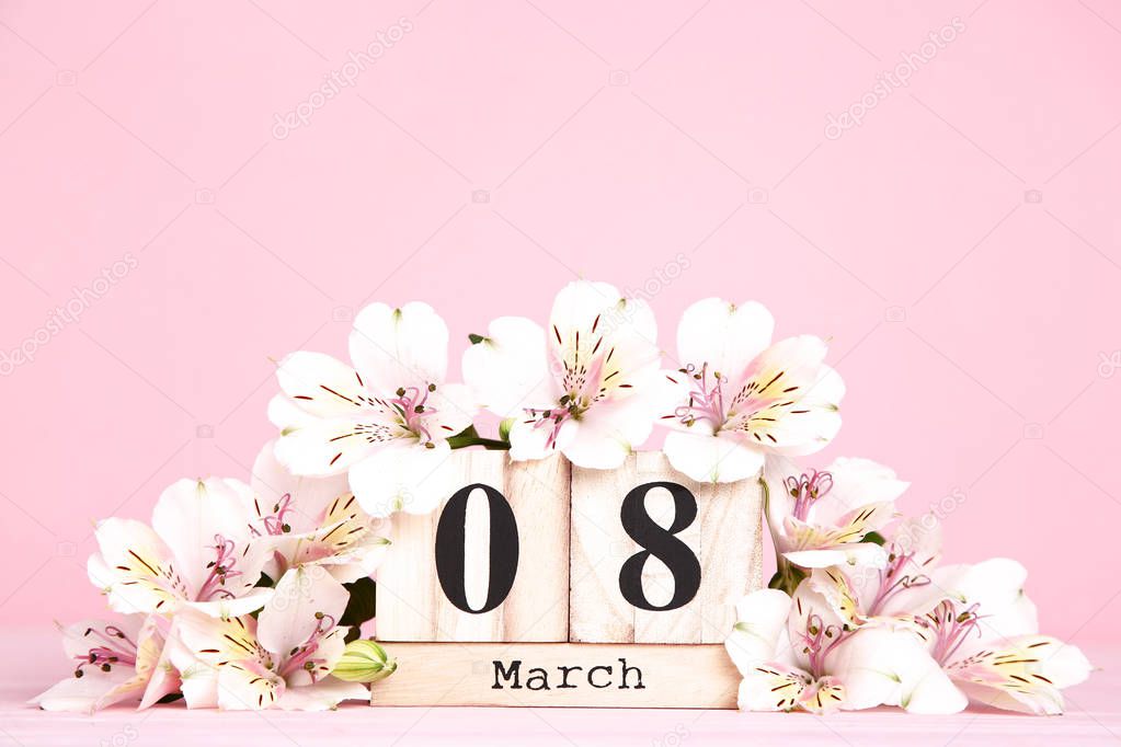 Women's Day on wooden calendar with alstroemeria flowers on pink background