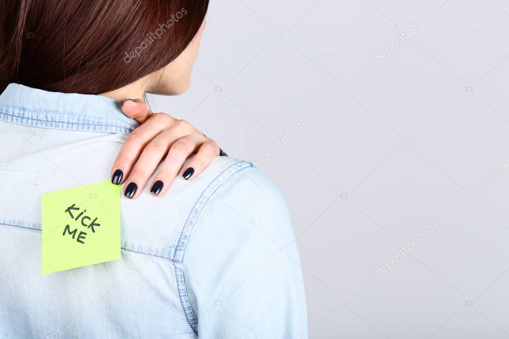 Female back attached paper note with text Kick Me