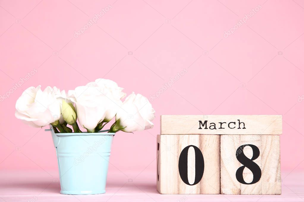 Women's Day on wooden calendar with eustoma flowers in pink bucket