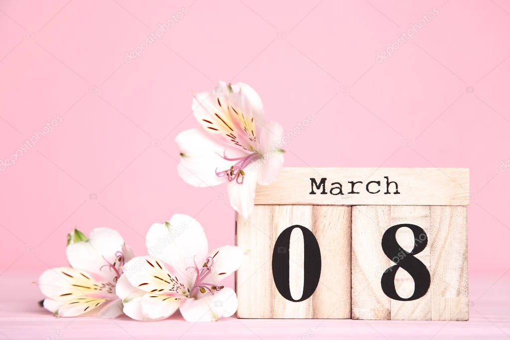 Women's Day on wooden calendar with alstroemeria flowers on pink background