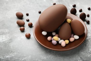 Gri ahşap masa üzerinde renkli şekerler ile çikolata Paskalya yumurtaları