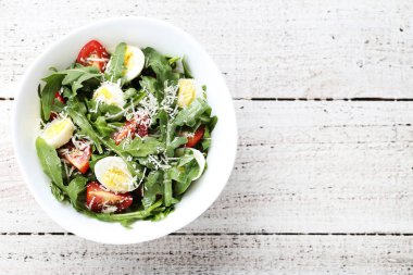 Roka salatası yapraklar, domates ve ahşap masa üzerinde yumurta