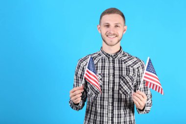 Genç adam bir Amerikan bayrağı mavi arka plan üzerinde tutan