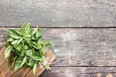 Kesme tahtası üzerinde gri ahşap masa ile yeşil fesleğen yaprakları