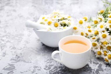 Gri arka plan üzerinde papatya çiçeği ile çay