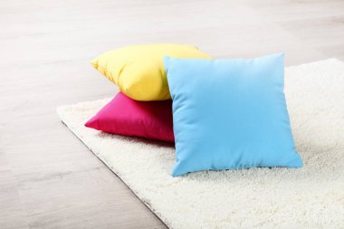 Yumuşak halı üzerinde ahşap renkli yastıklar ile laminat döşeme