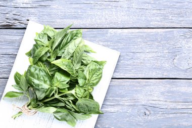 Kesme tahtası üzerinde gri ahşap masa ile yeşil fesleğen yaprakları