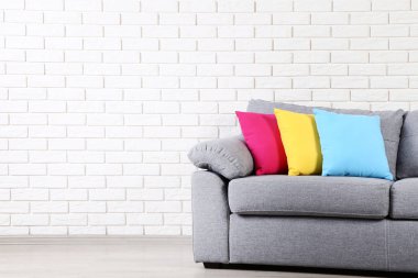 Tuğla duvar arka plan üzerinde renkli yastıklar ile modern gri kanepe