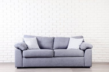 Modern gri kanepe yastık üzerinde tuğla duvar arka plan ile