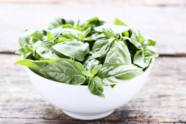 Kase gri ahşap masa üzerinde yeşil fesleğen yaprakları