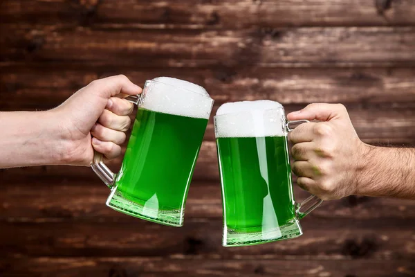 Den svatého Patrika. Skleněné hrnky s zelené pivo v mužských rukou na w — Stock fotografie