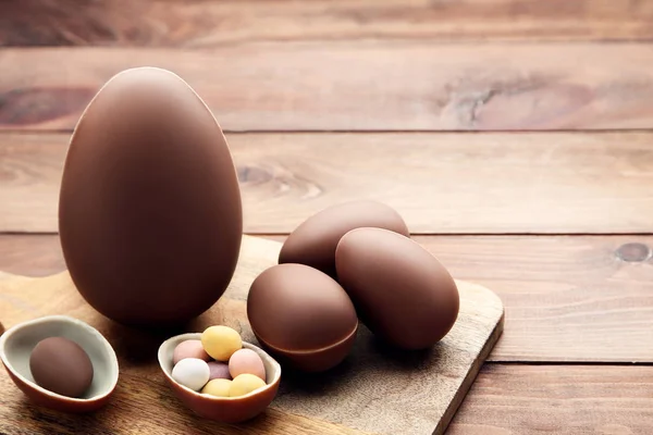 Huevos de Pascua de chocolate con tabla de cortar en mesa de madera — Foto de Stock