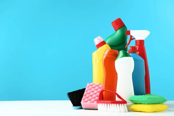 Botellas con detergente y herramientas de limpieza sobre mesa de madera — Foto de Stock