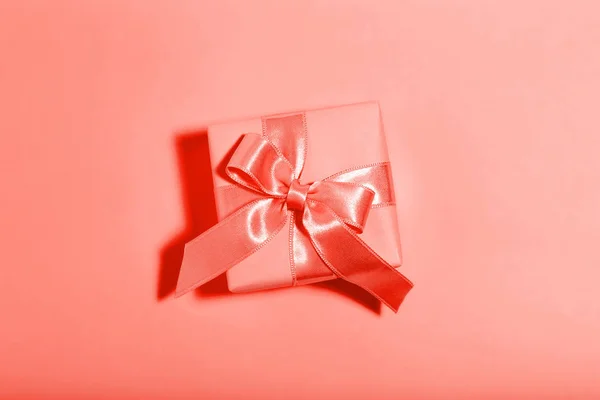 Gift box with ribbon bow on living coral color background. Minim — Stock Photo, Image