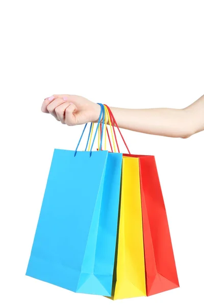 Mão feminina segurando sacos de compras coloridos no fundo branco — Fotografia de Stock