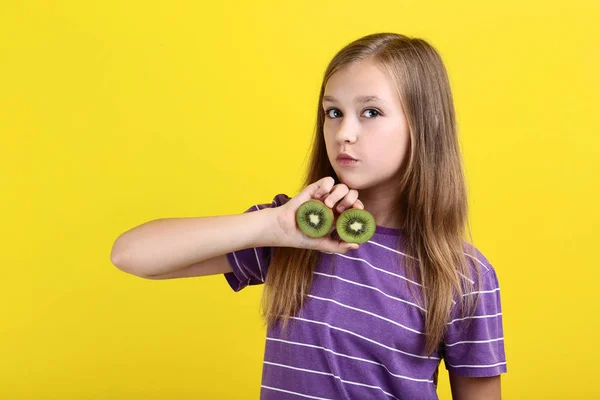 Милая молодая девушка с фруктами киви на желтом фоне — стоковое фото