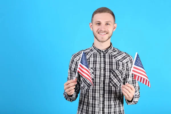 Genç adam bir Amerikan bayrağı mavi arka plan üzerinde tutan