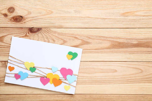 Handmade greeting card with paper hearts on brown wooden table