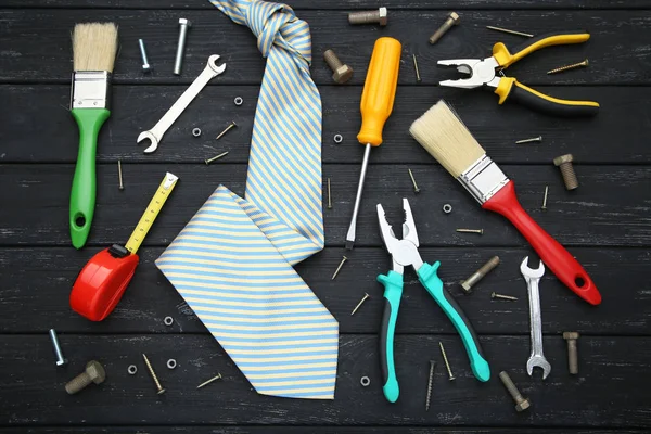 Diversi utensili con cravatta su tavolo in legno nero — Foto Stock