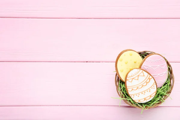 Galletas de pan de jengibre de Pascua en cesta sobre mesa de madera rosa —  Fotos de Stock