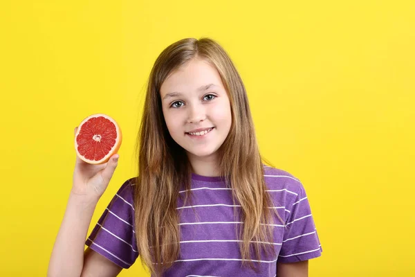 Carino giovane ragazza con pompelmo su sfondo giallo — Foto Stock