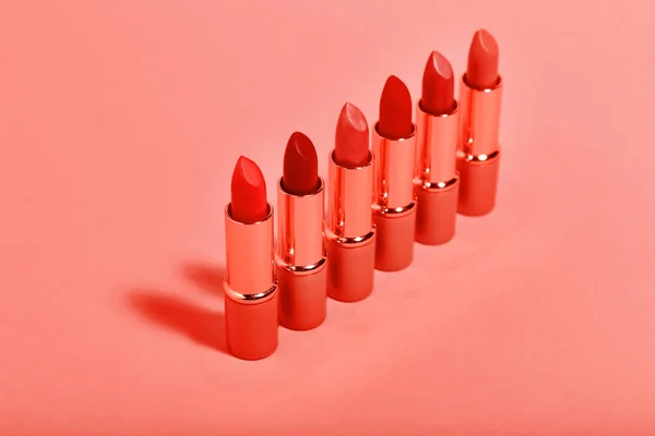 Lápices labiales de maquillaje sobre fondo de color coral vivo. Minimalismo co — Foto de Stock