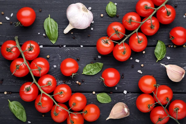 Tomat ceri dengan daun kemangi, bawang putih dan rempah-rempah pada woo hitam — Stok Foto