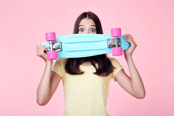 Νεαρό κορίτσι με skateboard σε ροζ φόντο — Φωτογραφία Αρχείου