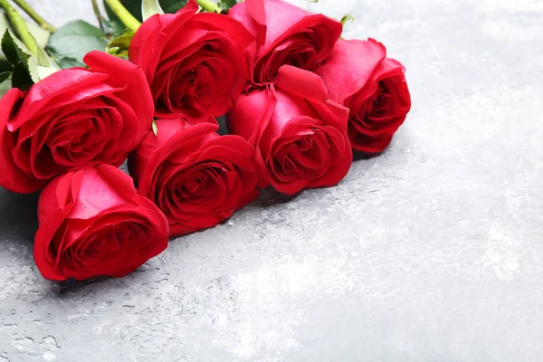 Ramo de rosas rojas sobre mesa de madera gris — Foto de Stock
