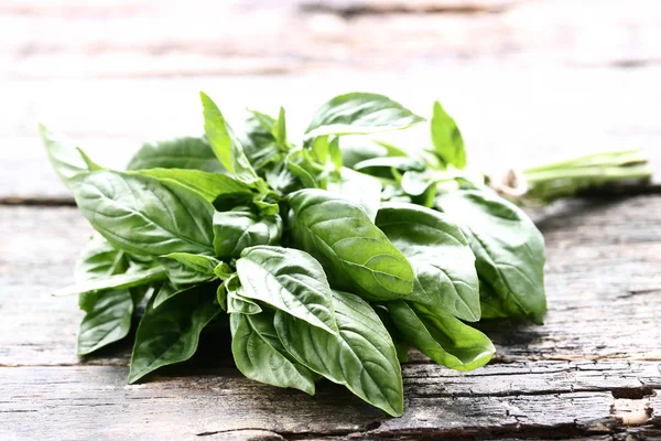 Green basil leafs on grey wooden table — Stock Photo, Image