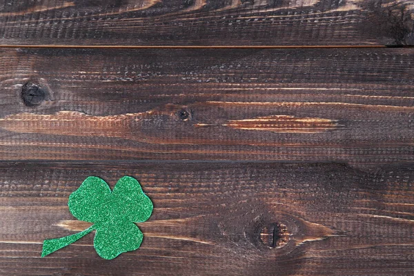 Green clover leaf on brown wooden table — Stock Photo, Image