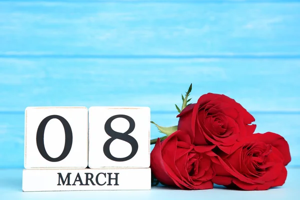 Festa della donna su calendario in legno con rose rosse su sfondo blu — Foto Stock