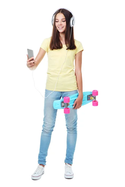 Young girl with skateboard, headphones and smartphone on white b — Stock Photo, Image