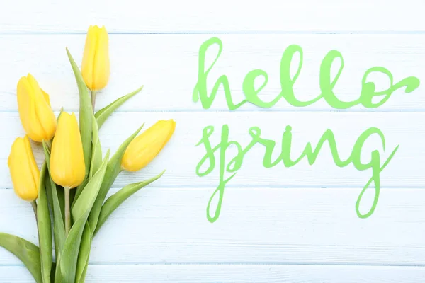 Ramillete de tulipanes amarillos con texto Hello Spring sobre mesa de madera — Foto de Stock