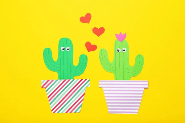 Paper cactuses with red hearts on yellow background. Minimalism concept