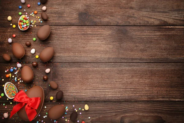 Kahverengi ahşap tabl üzerinde renkli şekerler ile çikolata Paskalya yumurtaları — Stok fotoğraf