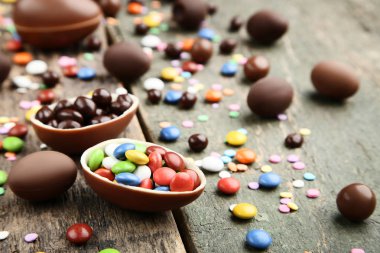 Gri ahşap masa üzerinde renkli şekerler ile çikolata Paskalya yumurtaları