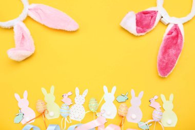 Paskalya tavşan kulakları sarı arka plan üzerinde renkli yumurta ile