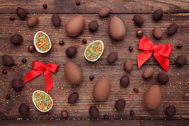 Kahverengi ahşap tabl üzerinde renkli şekerler ile çikolata Paskalya yumurtaları