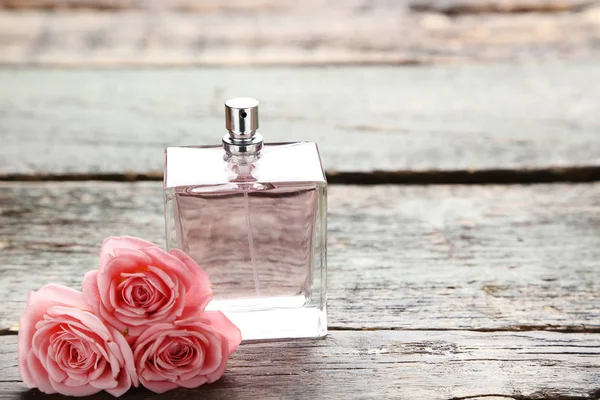 Flacon de parfum avec roses sur table en bois — Photo