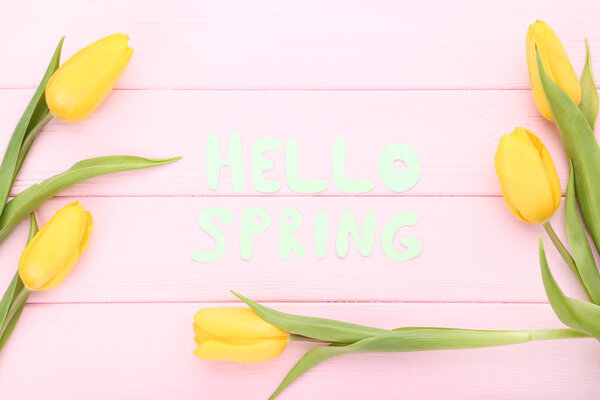 Bouquet of yellow tulips with text Hello Spring on wooden table