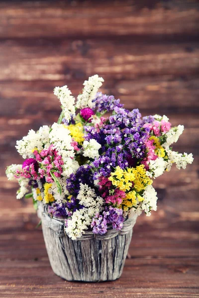 Spring flowers in basket on brown wooden table — Stock Photo, Image