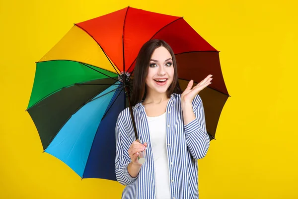 Young girl with colorful umbrella on yellow background — Stock Photo, Image