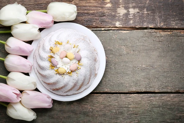 灰色の木製テーブルにチューリップの花を有する平板のイースター ケーキ — ストック写真