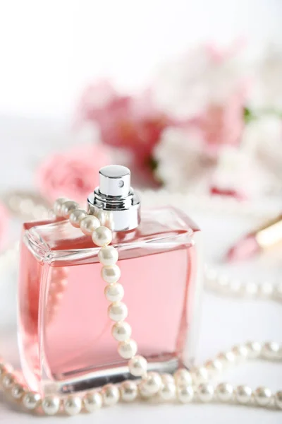 Parfümflasche mit Perlen auf weißem Hintergrund — Stockfoto