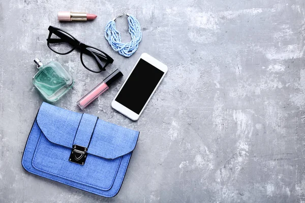 Bolsa com cosméticos, smartphone e óculos em t de madeira cinza — Fotografia de Stock