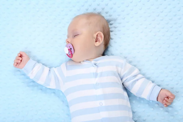Bayi laki-laki dengan soother tidur di tempat tidur biru — Stok Foto