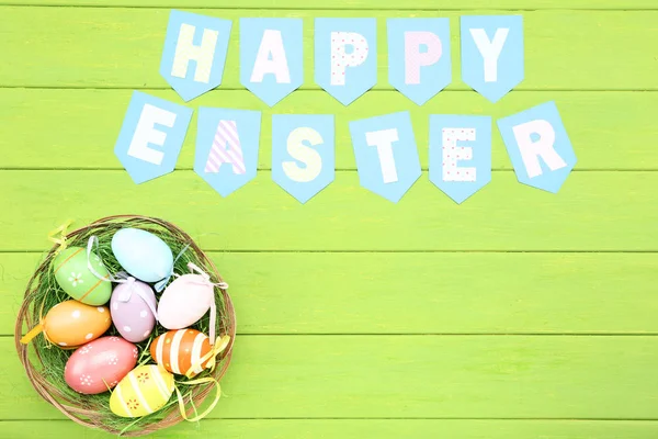 Texto Feliz Pascua con huevos de Pascua en la mesa de madera verde — Foto de Stock