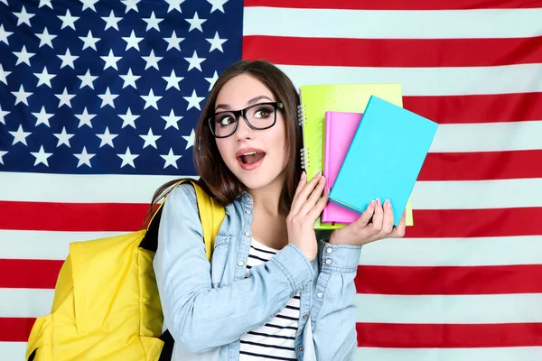 Joven estudiante con mochila y libros sobre fondos de bandera estadounidense — Foto de Stock